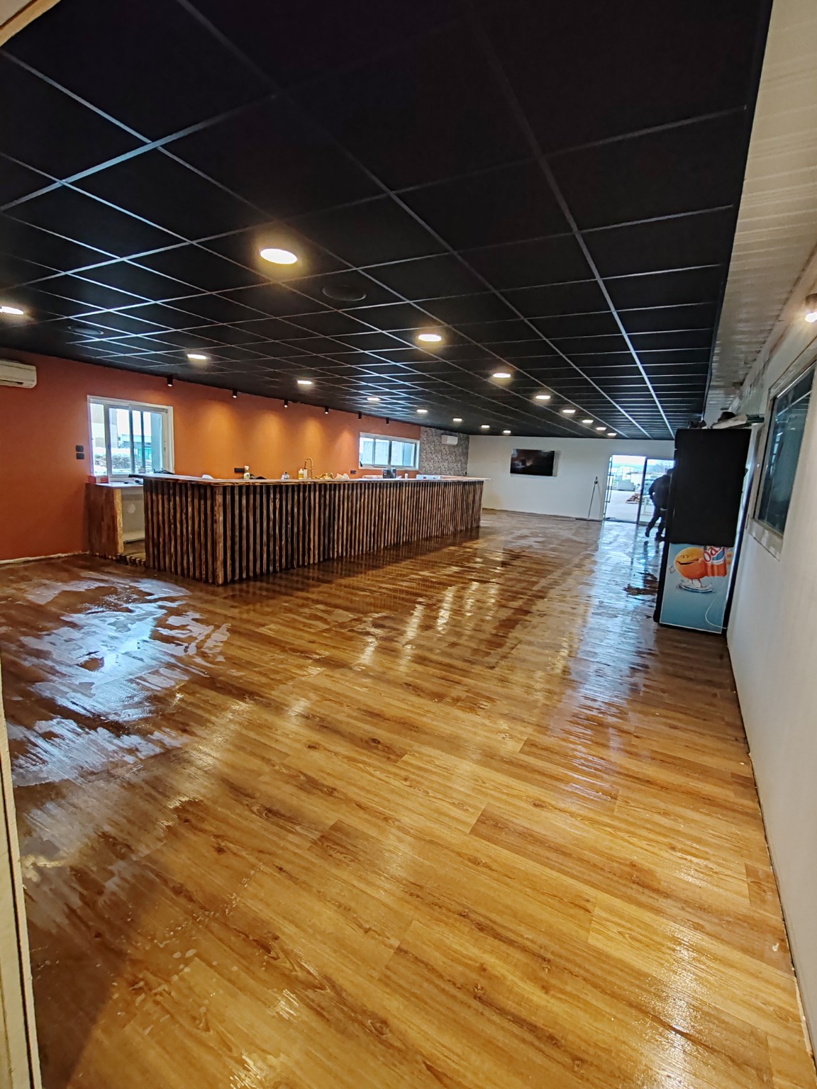 Le bar en bois, le sol et le faux plafond sombre du club-house de Break Padel.