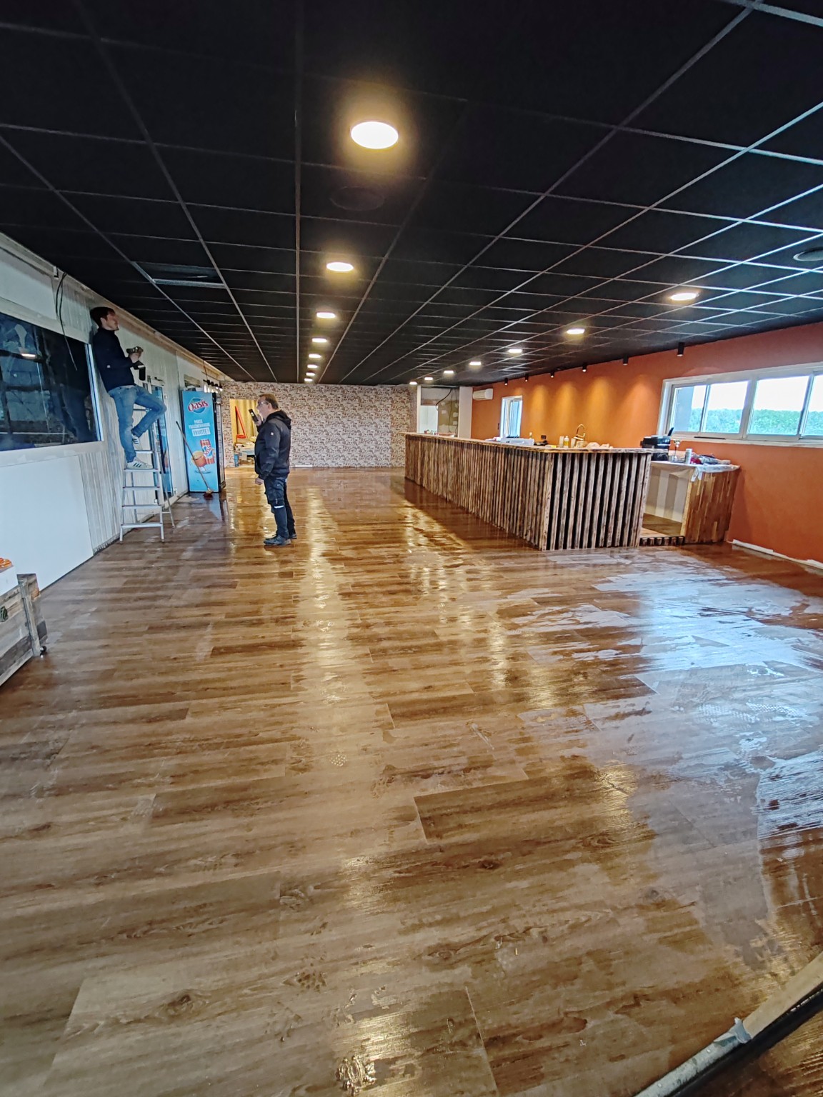 Une autre vue du club-house de Break Padel pendant les finitions, avec le bar et le sol aspect bois.