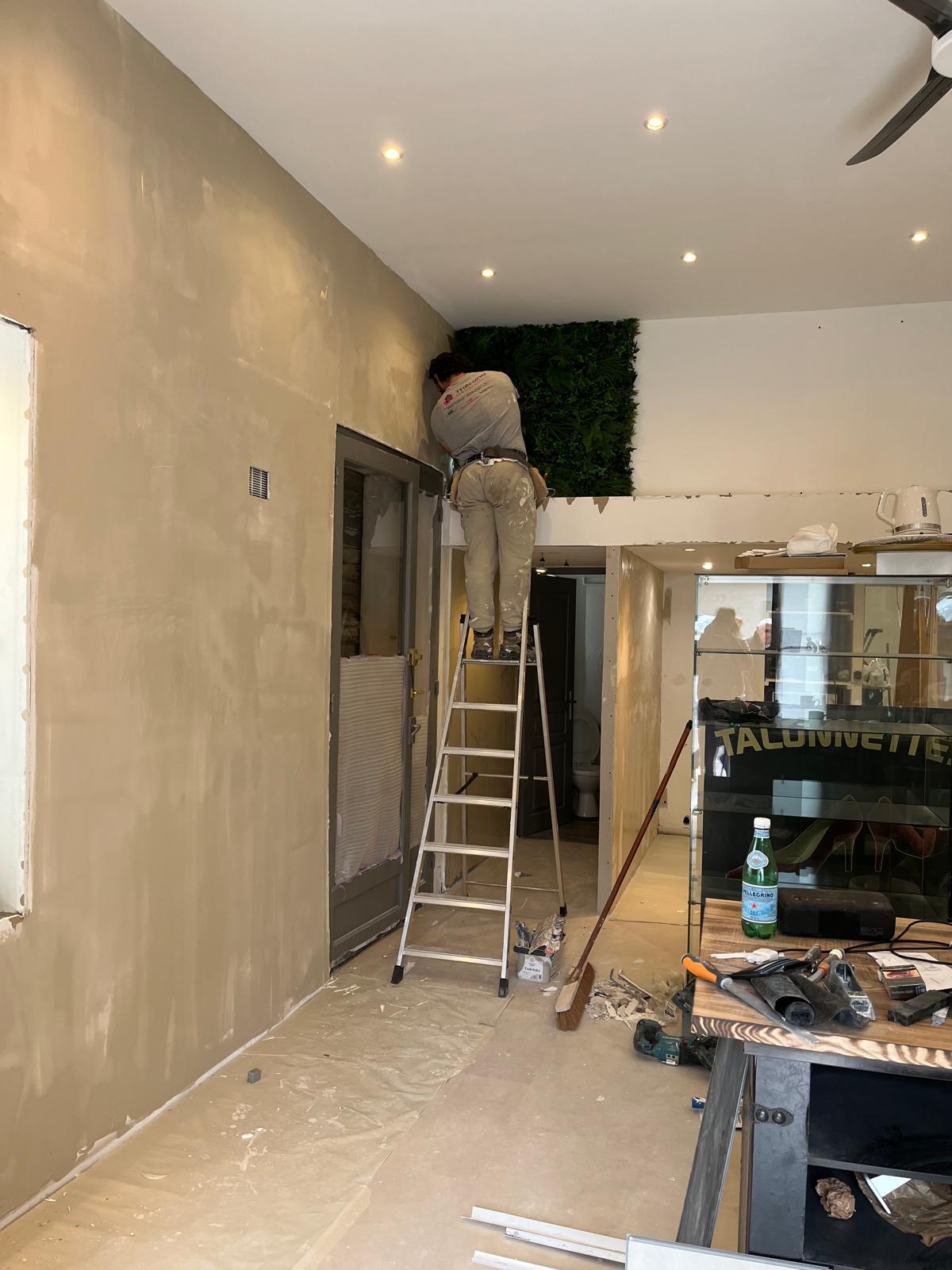 Travail sur les murs du local Maison Mégane, avec un artisan sur une échelle.