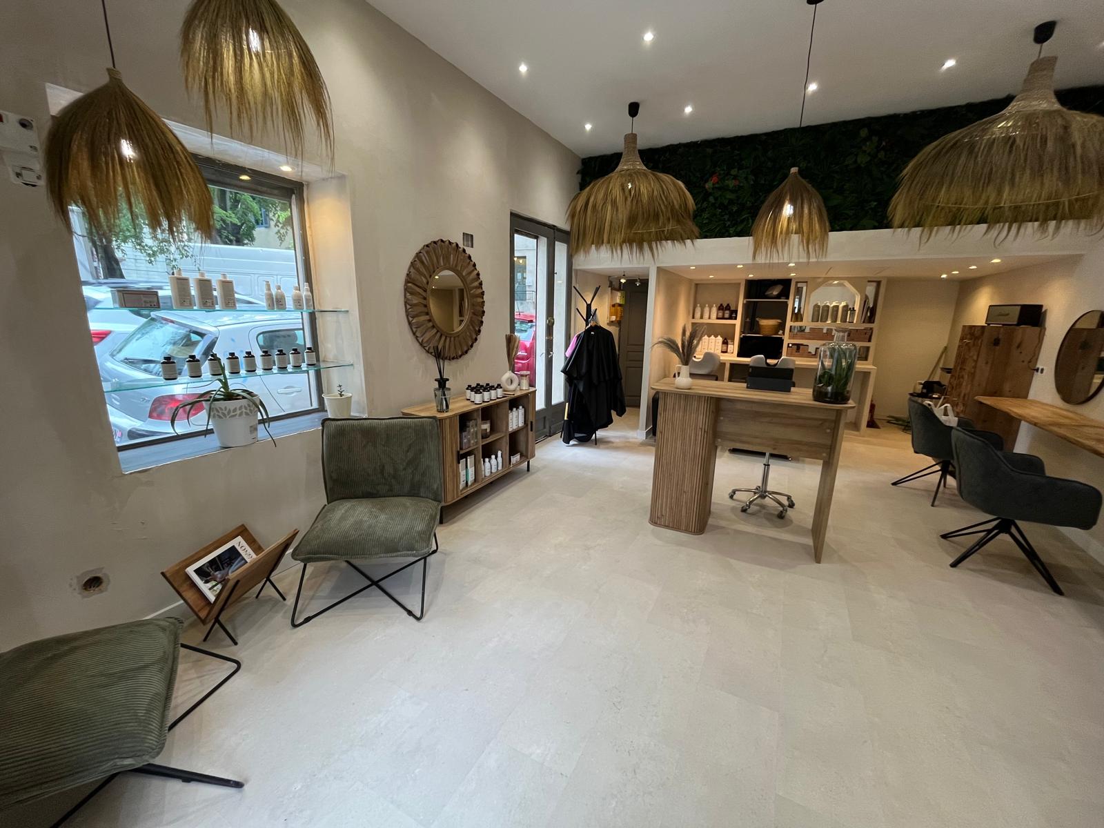 Vue d’ensemble du salon Maison Mégane terminé, avec le comptoir, les postes de coiffure et les suspensions.
