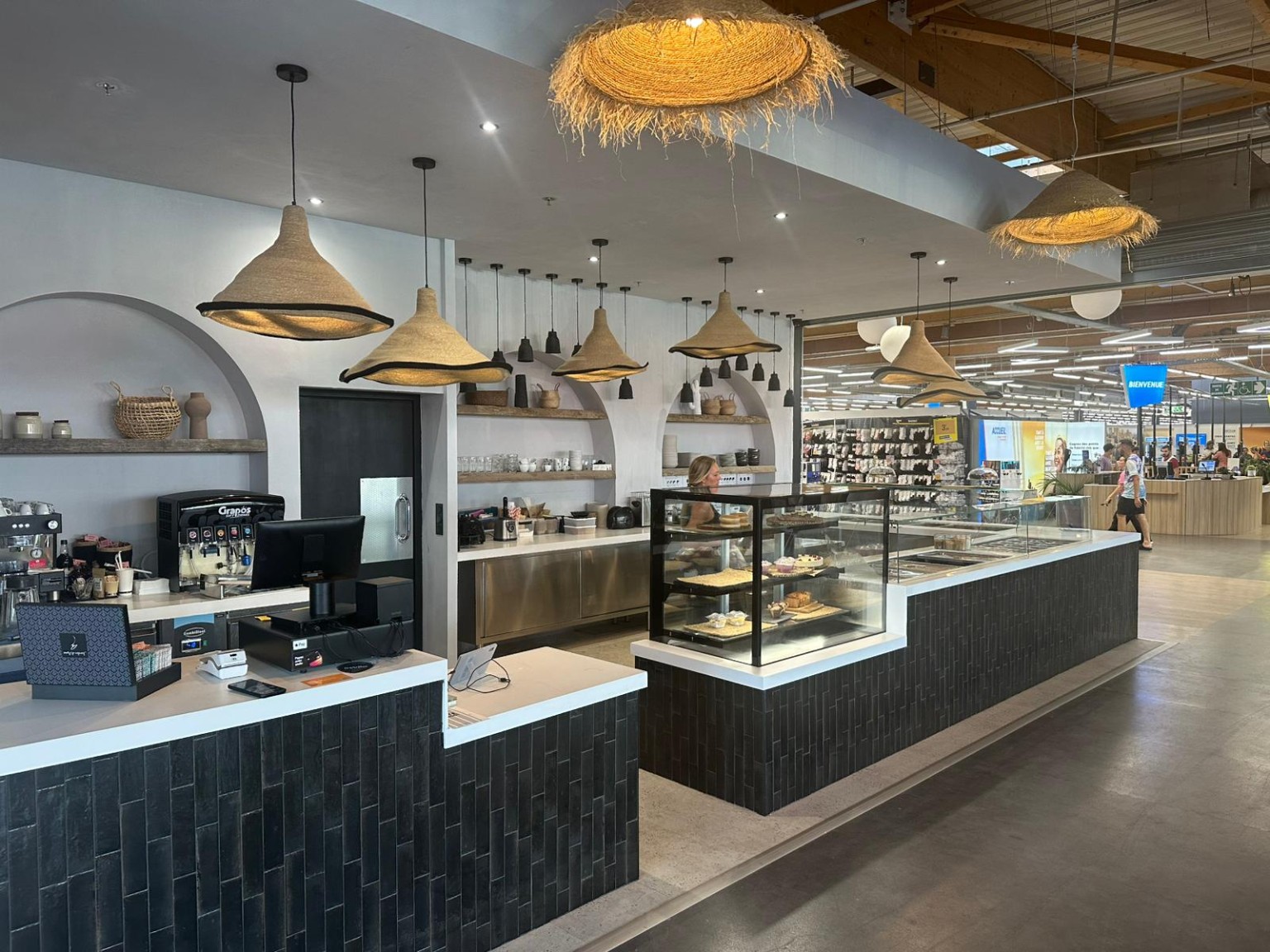 Vue d’ensemble du restaurant Pansy : comptoir, arches, enduit mural et suspensions en fibres naturelles.